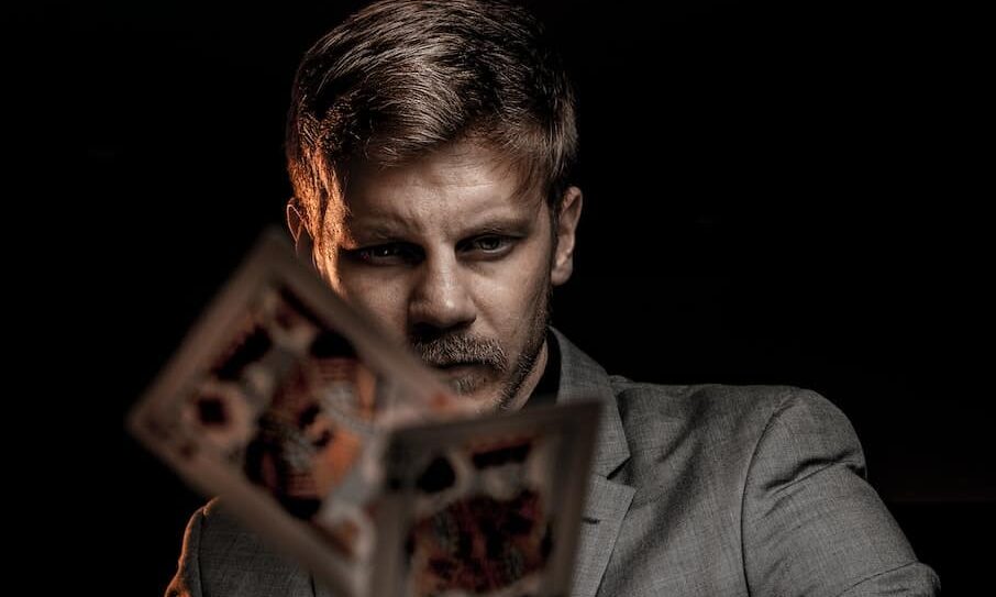 man in gray suit jacket holding jack of diamonds playing card
