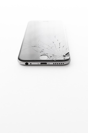 A broken cell phone on a white surface Description automatically generated