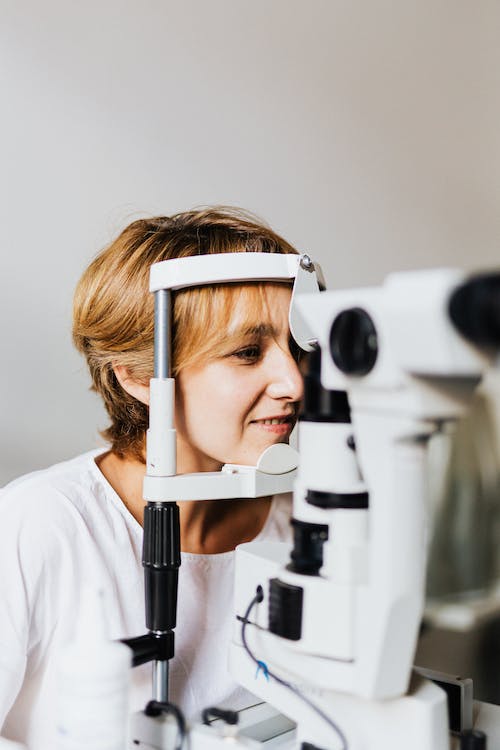 Free A Woman in White Shirt Having an Eye Test Using an Equipment Stock Photo