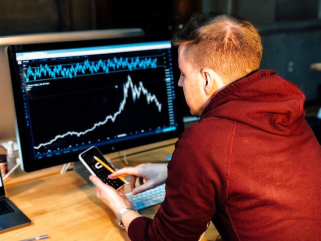 A trader using a phone, Kagi chart, and candlestick chart to monitor price movements.