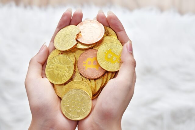 person holding gold round coins