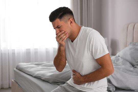 Man suffering from nausea on bed at home. Food poisoning