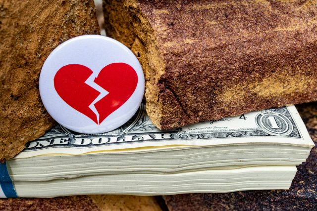 A broken heart on top of a stack of money