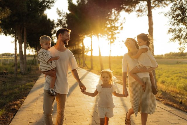 Family walking on path with trees at sunset
